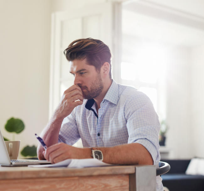 Man considering the cost of life coach training in the UK while working at his laptop