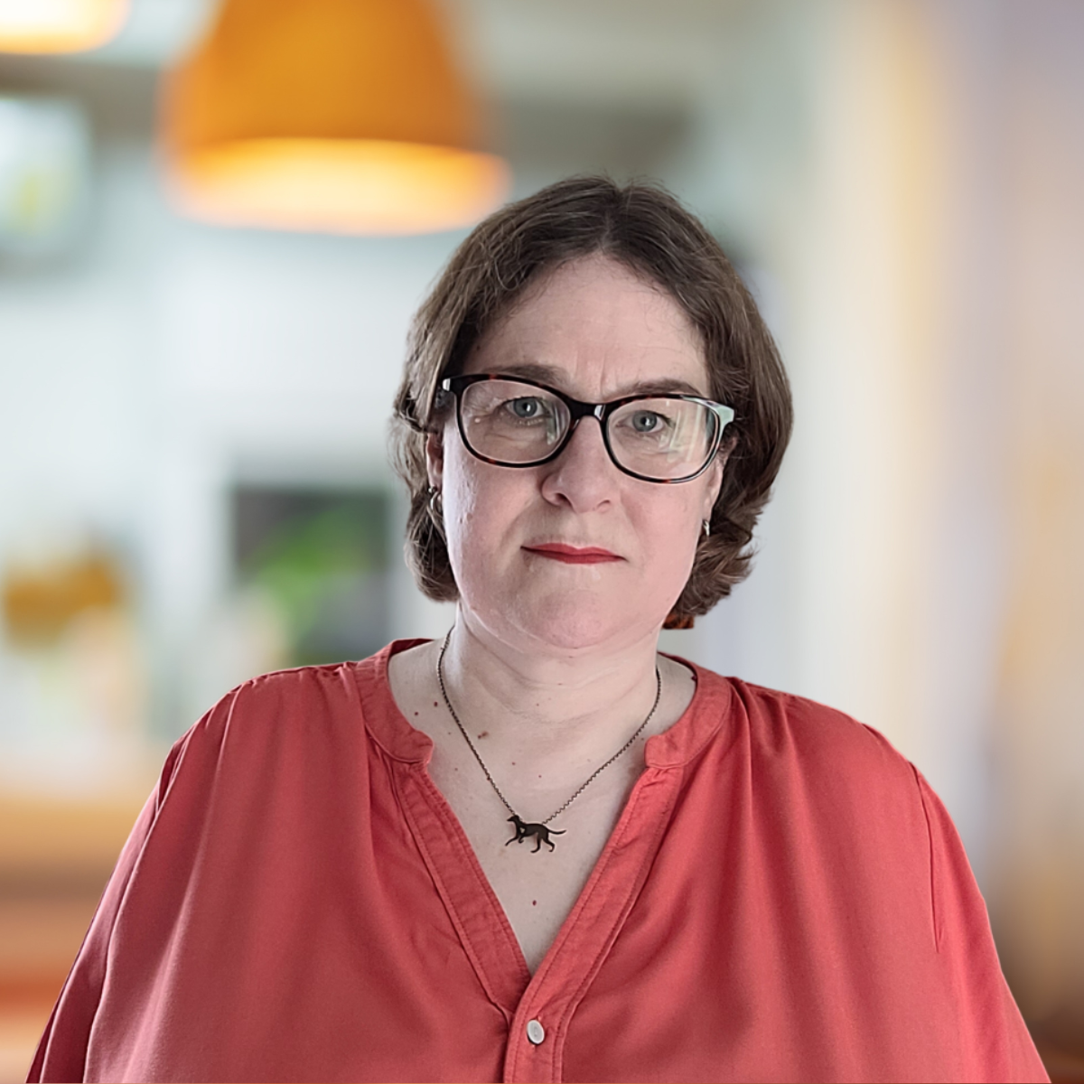 Woman with orange shirt standing in front of beige background