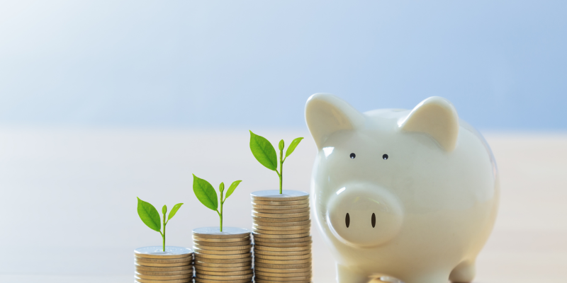 Piggy bank and growing coin stacks representing the investment in life coach training in the UK