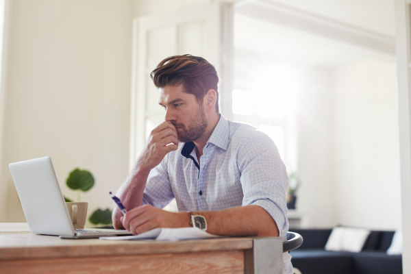 Man considering the cost of life coach training in the UK while working at his laptop